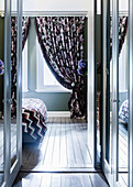 View through open glass door into the bedroom, curtain with a flower pattern at the window