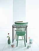 Mint-green wooden chair at black table and retro crockery arranged on white floor