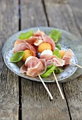 Melon and mozzarella skewers with raw ham and basil