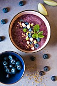 Smoothie bowl made with blueberries and apple, granish with leenseeds and mint, view from above