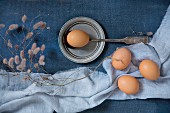 Hens' eggs and vintage spoon on blue fabrics