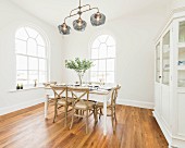 A white dining room with round arched windows and a covered dining table in an old building