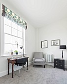 A study with a gray carpet, an armchair and an antique desk