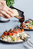 Parmesan wird auf Spaghetti Caprese mit gerösteten Tomaten gerieben