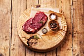 Raw fresh meat Ribeye Steak with salt and pepper on wooden background