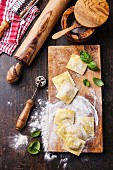 Raw Homemade Ravioli with pasta cutter on dark wooden background