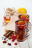 Cup of Hot winter raspberry tea with cinnamon sticks, lemon and star anise