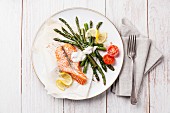 Grilled salmon with asparagus on white wooden background