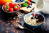 Diet breakfast: Bowls of oat flake, berries and fresh milk on wooden background