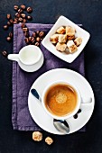 Tasse Kaffee mit braunen Zuckerwürfeln und Milchkännchen (Aufsicht)