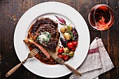 Sliced medium rare grilled Beef steak Ribeye with herb butter and baby potatoes and wine