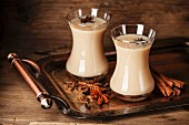 Hot tea with milk and spices on dark background