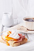 Breakfast with cup of coffee and toast with cheese and poached egg served on white wooden table