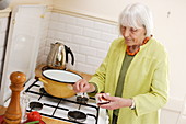 Elderly woman using gas burner