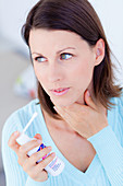 Woman using spray for sore throat