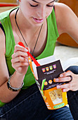 Teenage girl eating Pasta Box