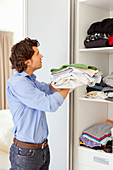 Man organizing clothes in cupboard