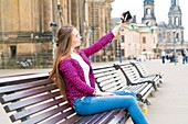Young woman taking photo of herself with camera