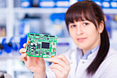 Woman holding circuit board, portrait