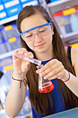 Girl pouring liquid into chemical flask