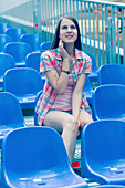 Young woman sitting on blue plastic seat