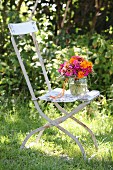 Farbenfroher Blumenstrauss mit Zinnias und Tagetes auf Vintage Gartenstuhl