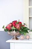 Festive Christmas arrangement of roses, pomegranates and ivy tendrils in silver dish