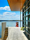 Terrace with concrete floor, glass balustrade and view of lake