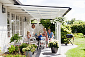 Family seated at table on roofed terrace in summery garden