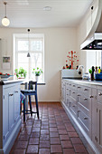 Terracotta floor tiles in bright country-house kitchen