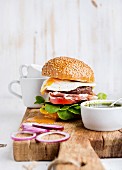 Fresh homemade burger with beef cutlet, egg, prosciutto and vegetables on wooden serving board