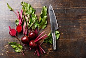 Red Beetroot with herbage green leaves and Kitchen knife on wooden background