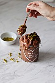 Vegan chocolate banana ice cream with melted dark chocolate and pistachios in a jar