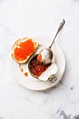 Salmon red caviar in can and sandwich on white marble background