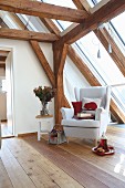 White wing-back chair and cushion with red felt hedgehog motif in cosy reading corner in converted attic