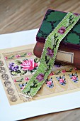 Glass-bead choker draped over wooden box and floral beading pattern