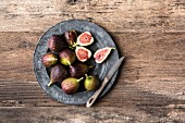 Whole and sliced figs on a grey plate on a wooden background
