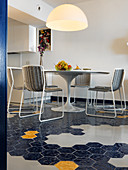 Round designer table and delicate chairs on hexagonal floor tiles