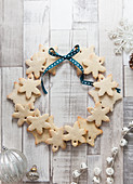Snowflake shaped biscuits arranged to make a Christmas wreath on a rustic white wood surface