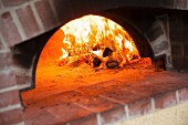 Brennendes Feuer im Holzofen einer Pizzeria