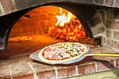 Pizza capricciosa in front of a wood oven