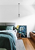 Bedroom with double bed, pendant lamp above bedside table and picture with flower motif