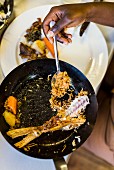 Remains of fried fish with wild rice and vegetables in a pan (South Africa)
