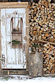 Alter Holzschlitten als Regal mit Axt und Tannenzweigen an rustikalem Holztür