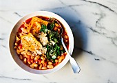 Cannellini beans and pasta in a tomato soup topped with kale and cheese