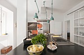 Schwarze Küchenarbeitsplatte mit Spülbecken und Armatur, darüber türkisfarbene Retro Leuchten