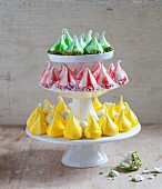 A cake stand with three different coloured meringue kisses