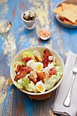 A lettuce salad with boiled eggs, bacon and spicy croutons