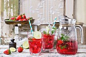 Selbstgemachte Erdbeerlimonade serviert mit Minze und Limetten in Gläsern und Krug