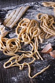 Making homemade pasta pici: sliced rolled dough for pasta and prepared long pasta on black slate board